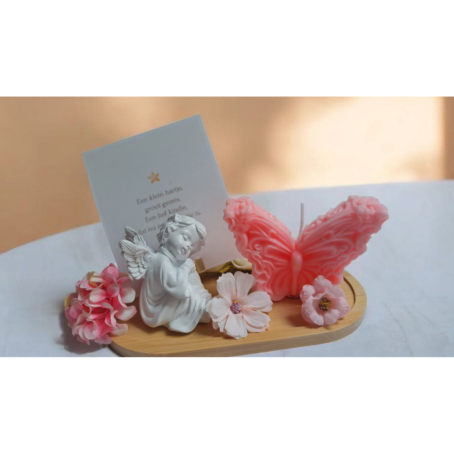 Stijlvolle herinneringskaars met bloemen en engel- of vlinderdecoratie, inclusief persoonlijk kaartje; perfect als troostgeschenk bij overlijden.