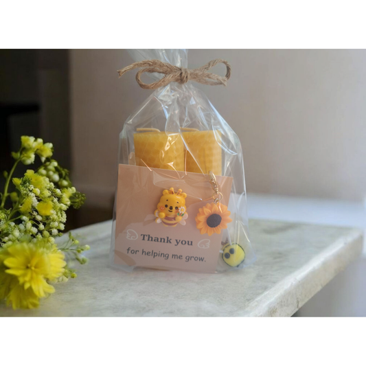 Twee bijenwaskaarsen met een kaartje met de tekst 'Thank you for helping me grow', inclusief een zonnebloem-sleutelhangertje – een attent juf of meester cadeau.
