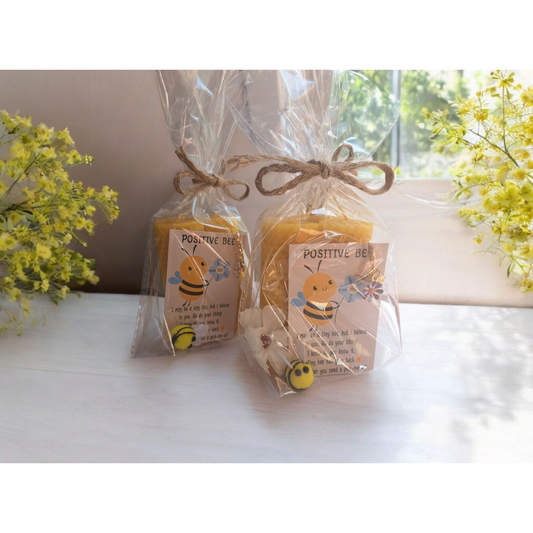 Twee handgerolde kaarsen van 100% pure bijenwas, met een kaartje met de tekst 'Positive Bee' en een opbeurende boodschap, stijlvol afgewerkt met natuurlijk touw en met zorg verpakt.