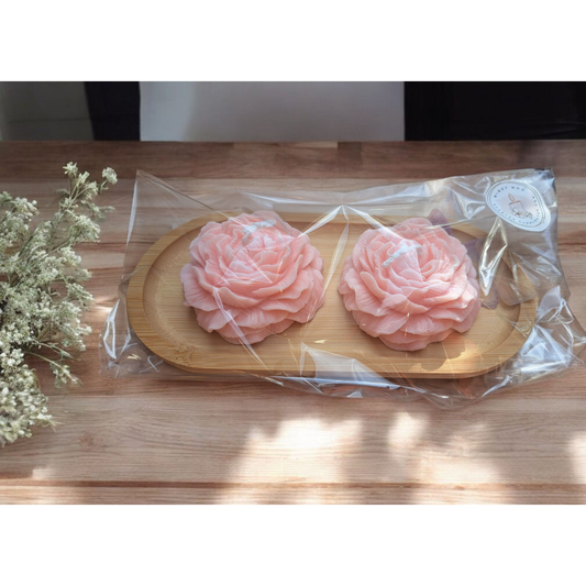 Twee pioenrozen decoratief gepresenteerd op een houten plankje – een elegante en natuurlijke eyecatcher.